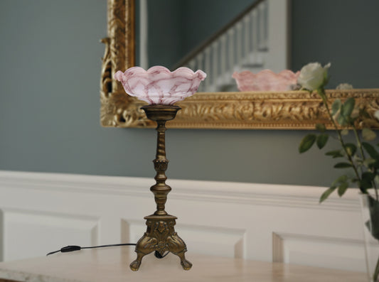Vintage solid brass candle holder converted to an elegant vintage table lamp . The solid brass pillar candle holder is one of a set we found in Brugge Belgium estimated early to mid-20th century. The pink shade is glass or opaline and dates from around the same time period.
