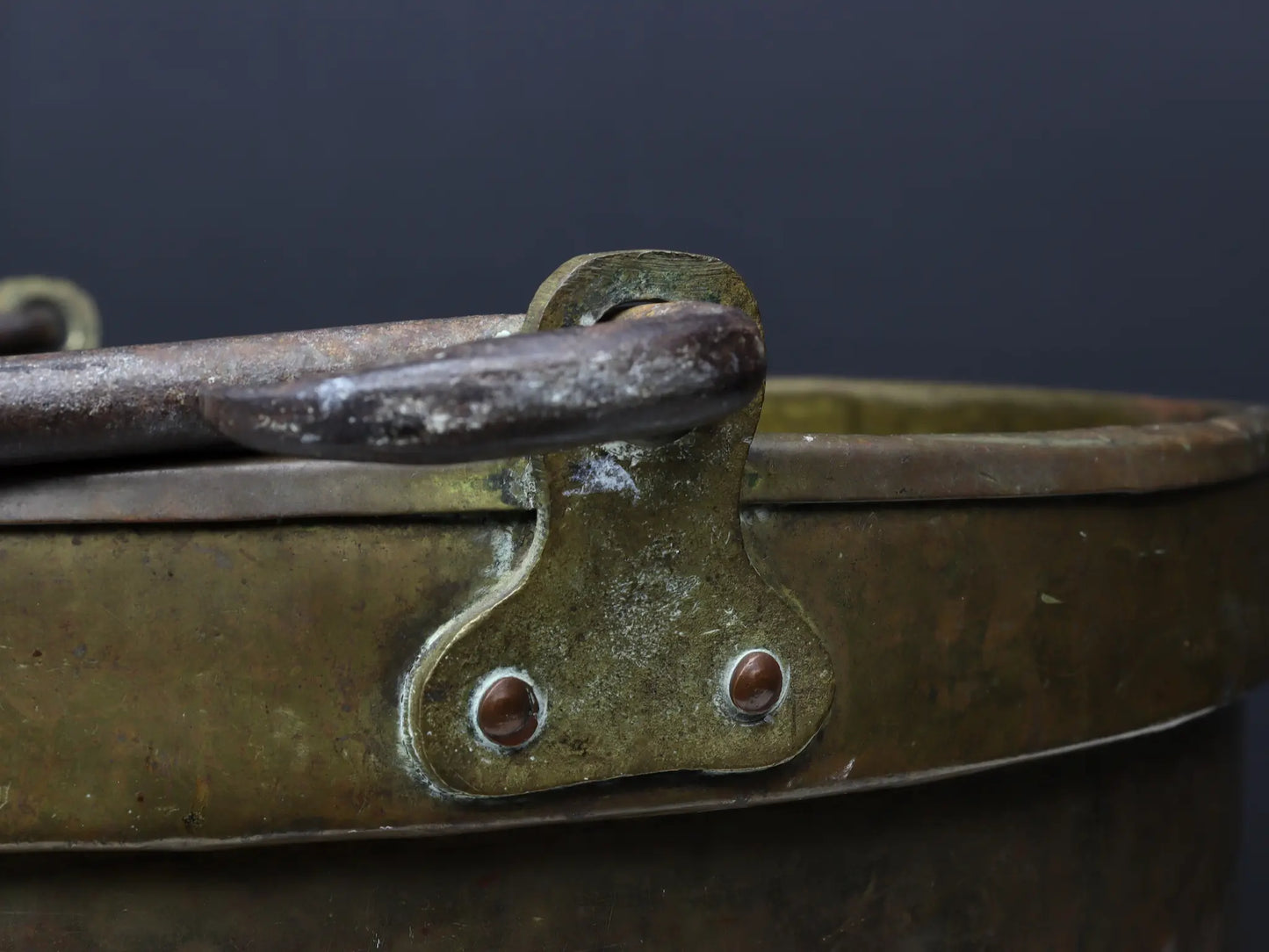 19th Century Dutch hand-hammered brass cauldron featuring a heavy-duty forged iron swing handle, authentic copper rivets, and a rolled rim detail.