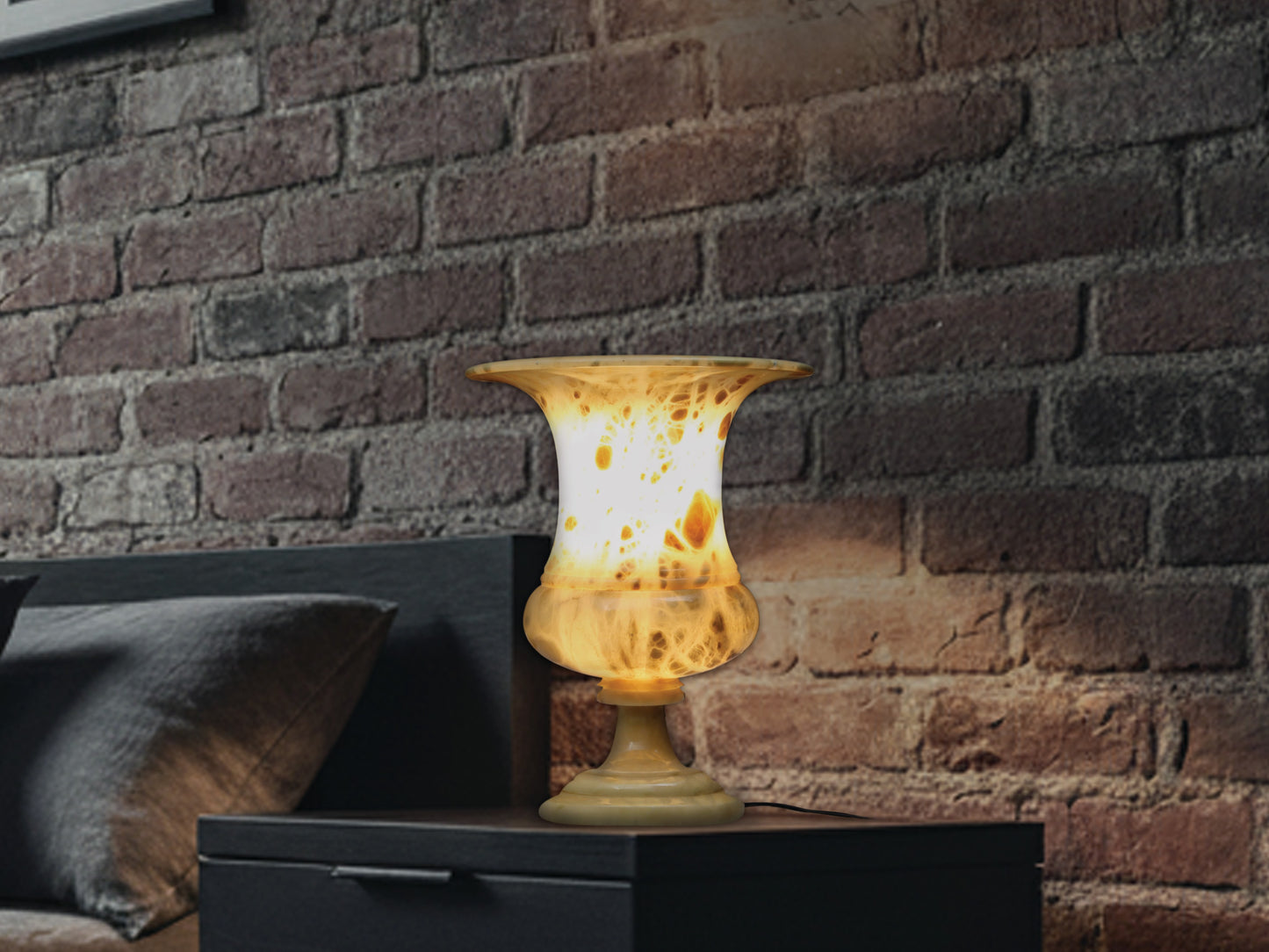 Mid-century yellow alabaster table lamp on a dark nightstand casting a warm, atmospheric glow on a brick wall.