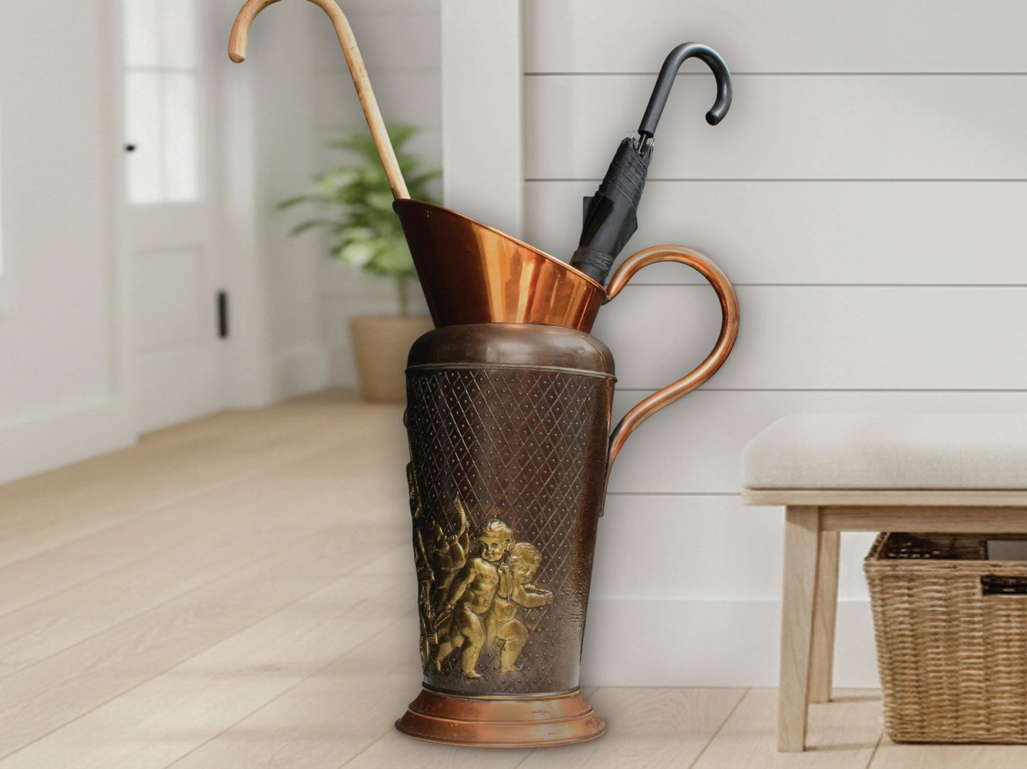 Vintage copper umbrella stand with brass cherub relief. Belgian mid-century home decor. Two-tone metal vessel with red copper rim and dark patina body featuring lattice texture. Rustic farmhouse cane holder or dried flower vase.